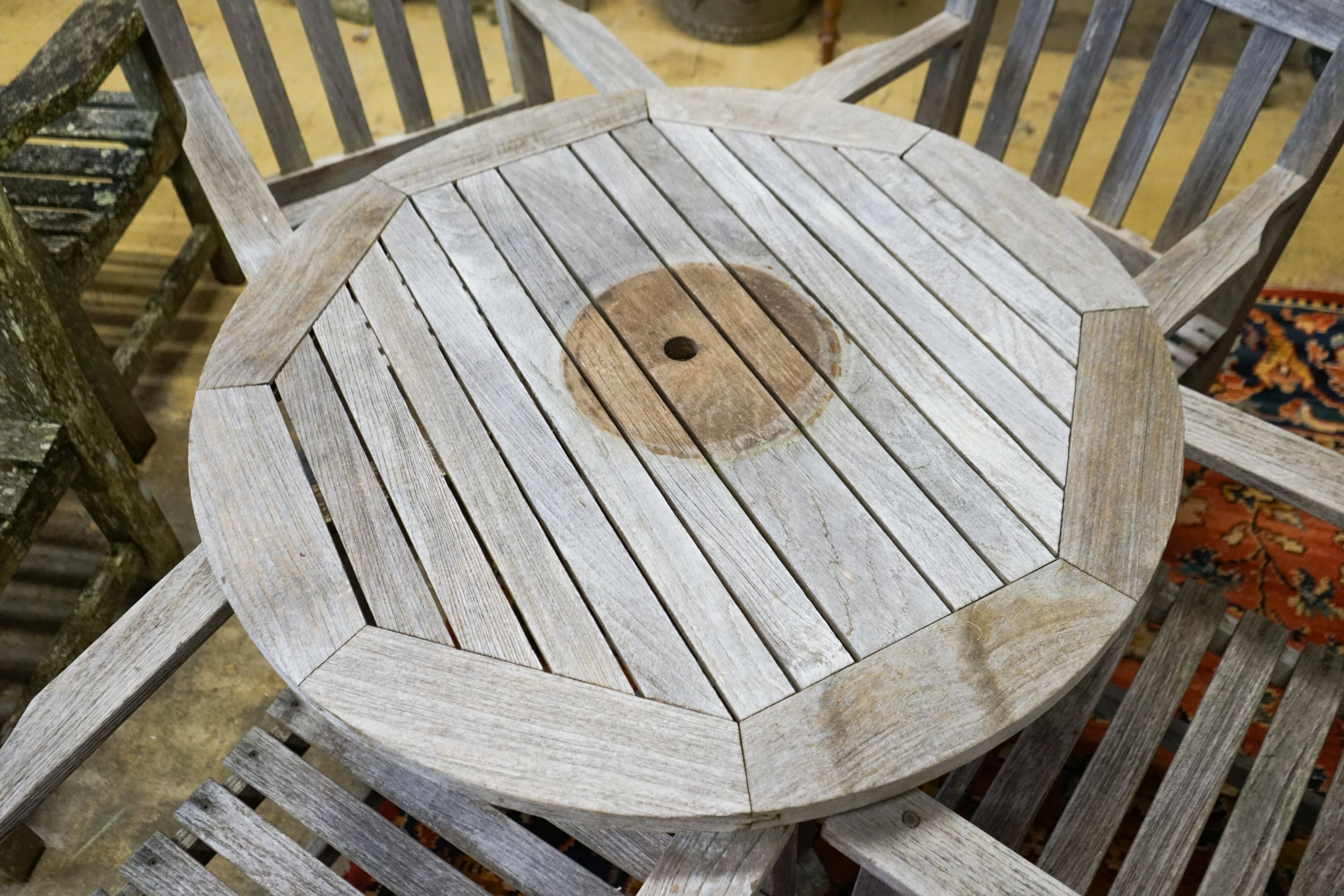 A set of four teak garden chairs and a circular parasol table, diameter 91cm chairs width 60cm